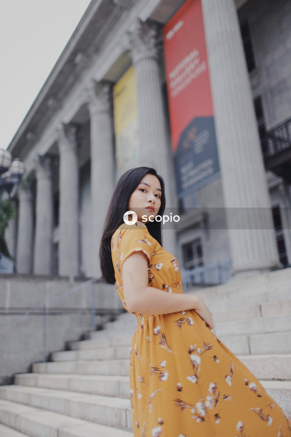 Asian woman in orange dress standing on stairs