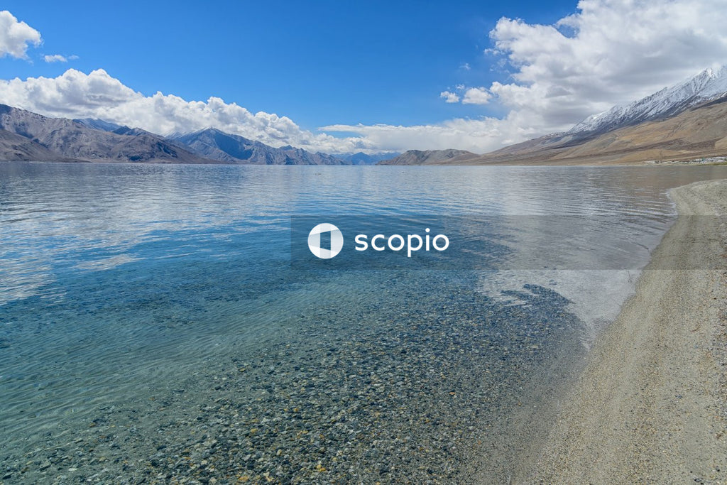 Blue body of water near brown mountain under blue sky