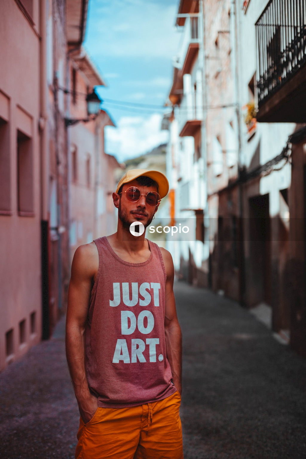 Portrait of man in shirt with text "Just Do Art" standing in an alley