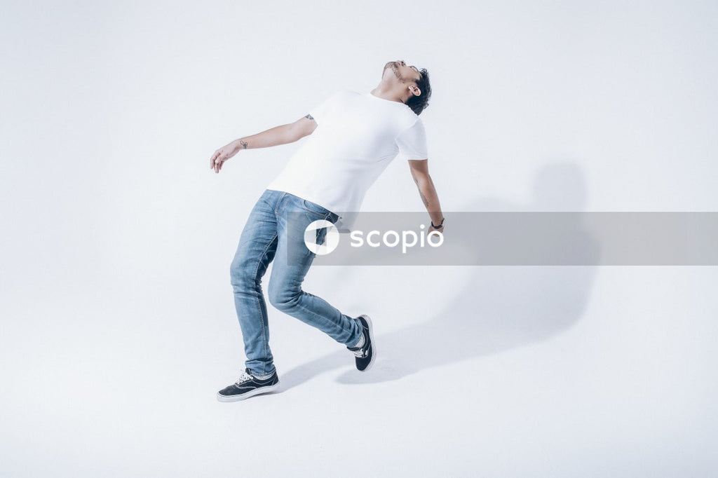 Man in white t-shirt and blue denim jeans falling backwards