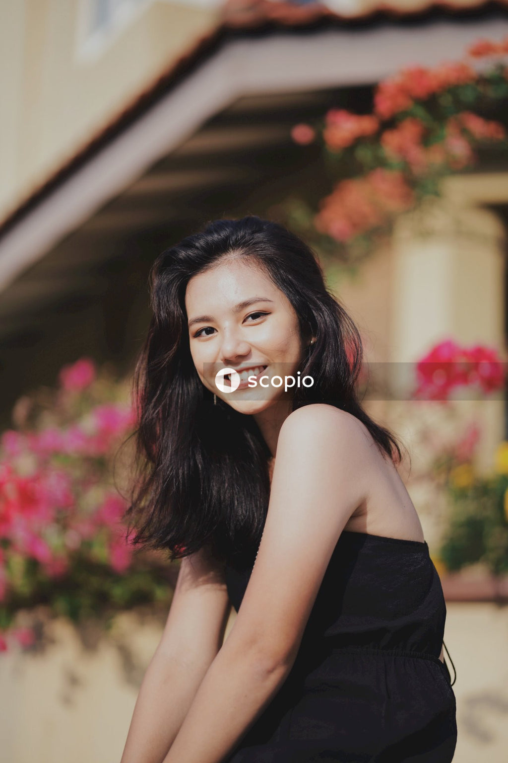 Woman in dark dress posing near flowers bushes