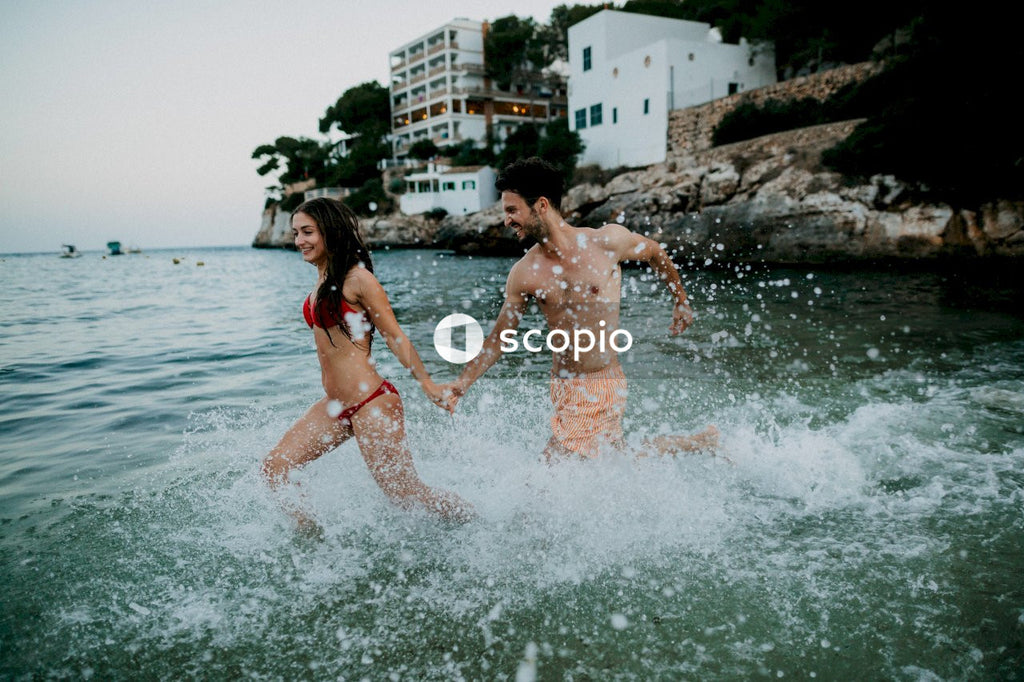 Man and woman in swimsuit running on shallow water