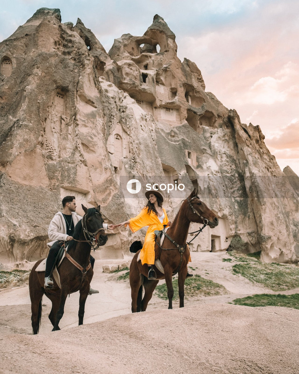 Man and woman riding horses near rocky mountains