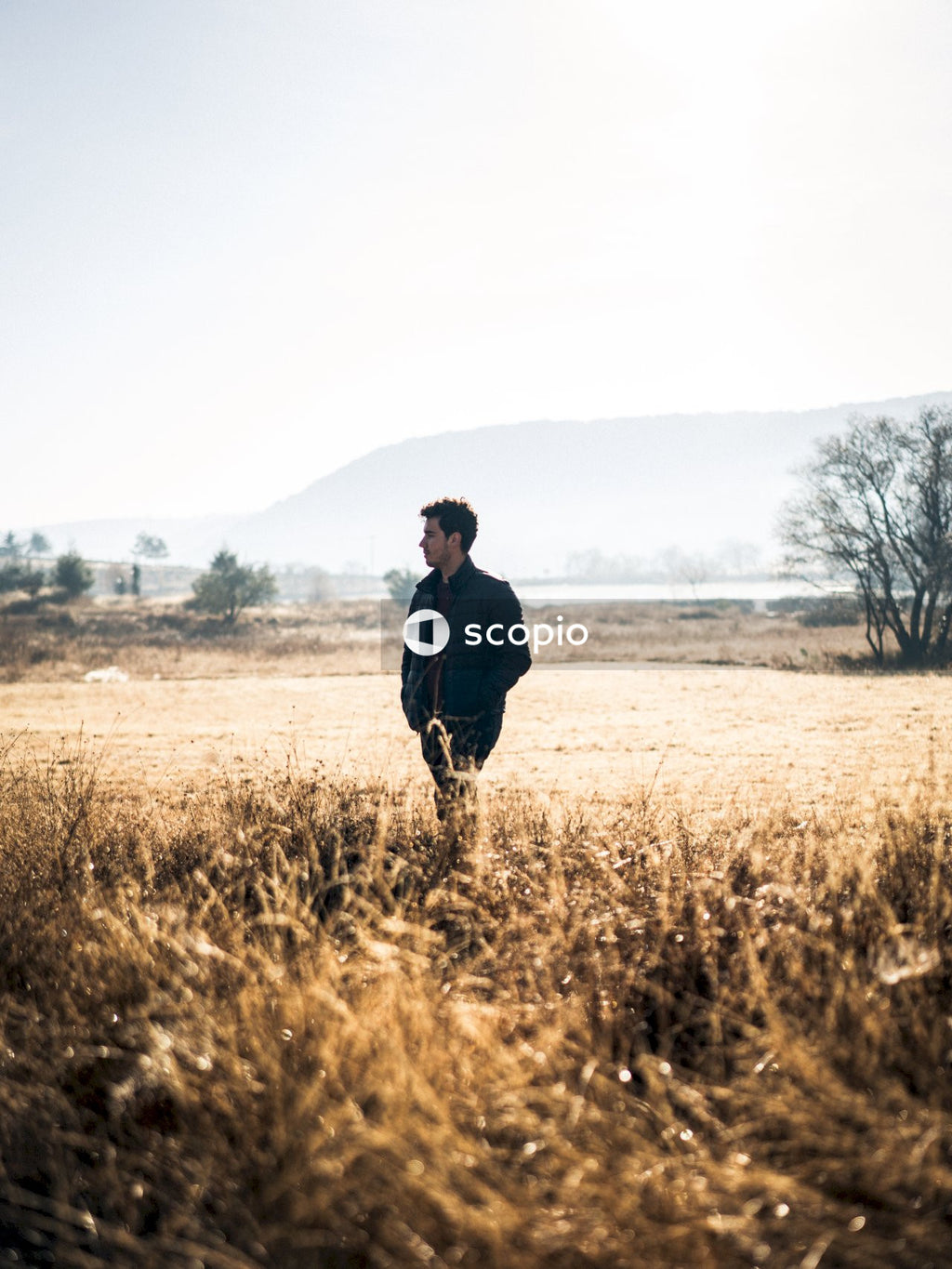 Man in black jacket walking on brown grass field