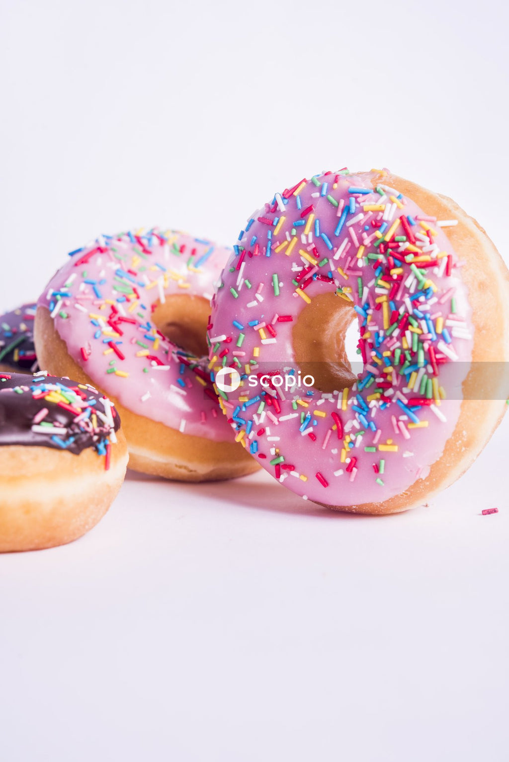 Two doughnuts with sprinkles on white surface