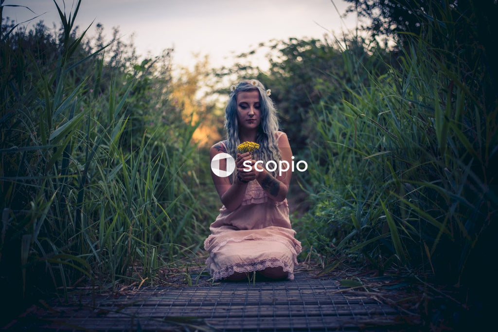 Woman in brown dress sitting on wooden pathway