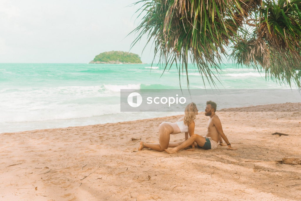 Blonde woman in swimsuit approaching a man on seashore