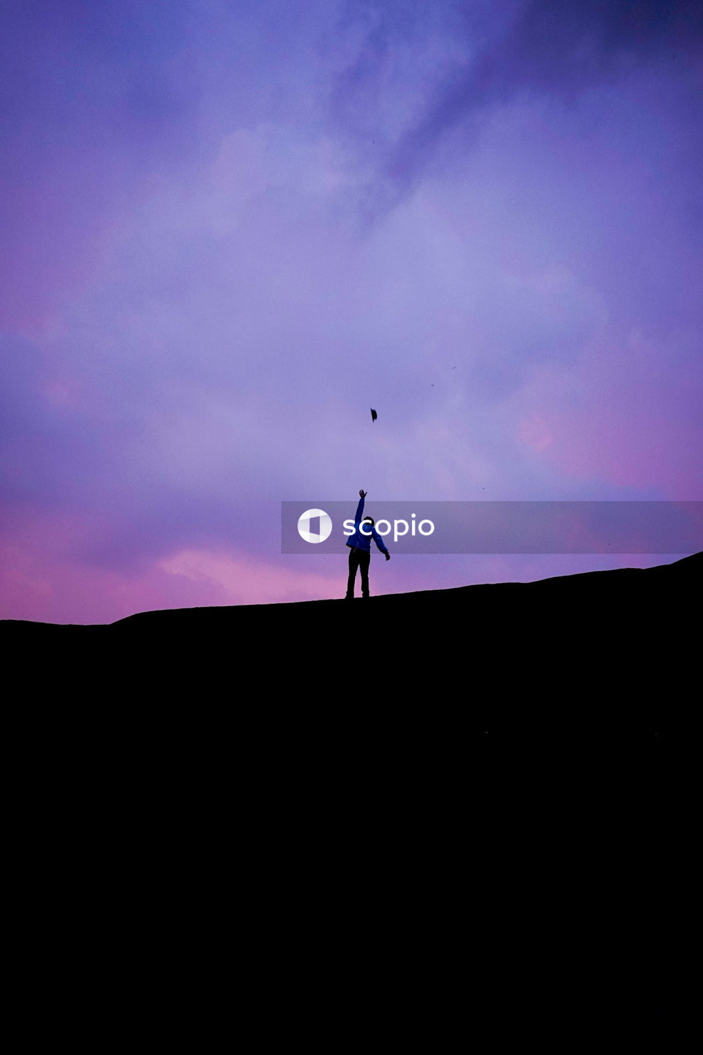 Silhouette of a person standing on hill under colorful sky