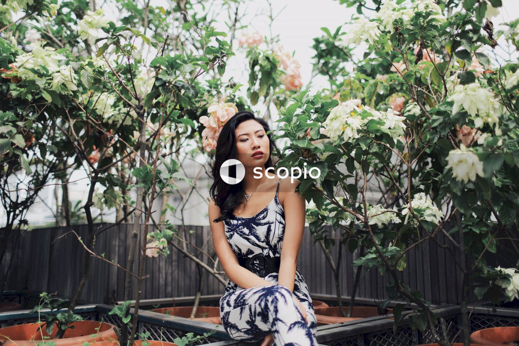 East Asian woman sitting in front of flowers with closed eyes