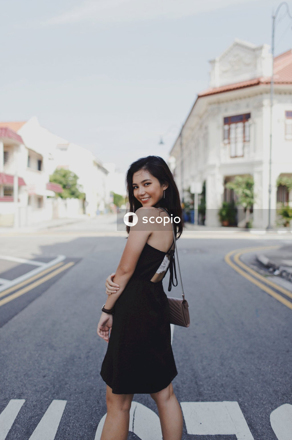 Woman in dark sleeveless dress standing on road