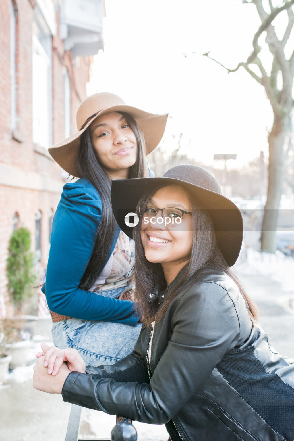 Two women wearing fedora hats on sidewalk