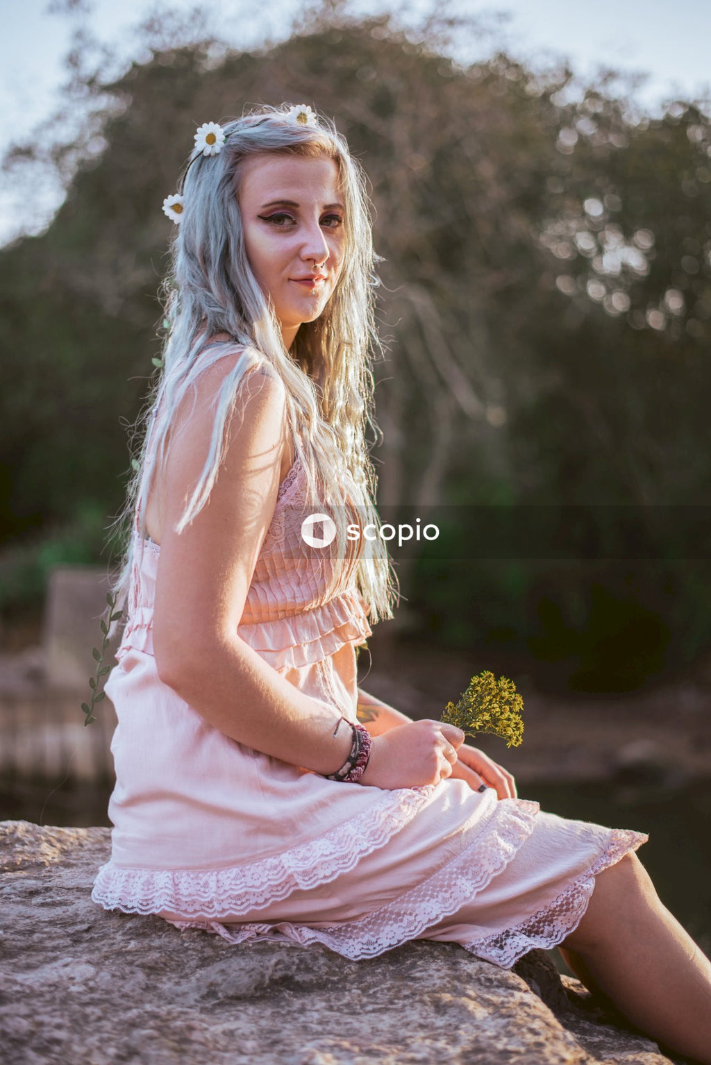 Woman in pink sleeveless dress holding yellow flowers