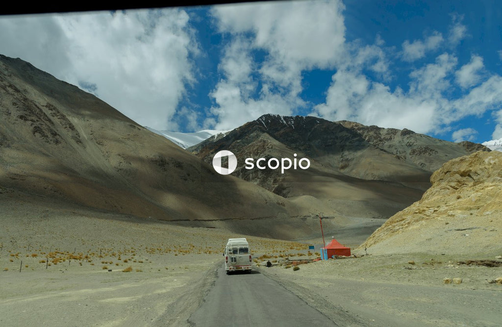 White van on road near brown mountain under blue sky