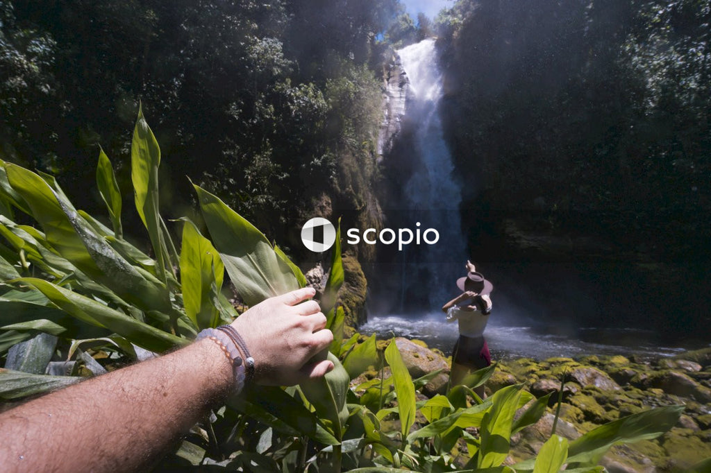 Person in white shirt standing on rock near waterfalls