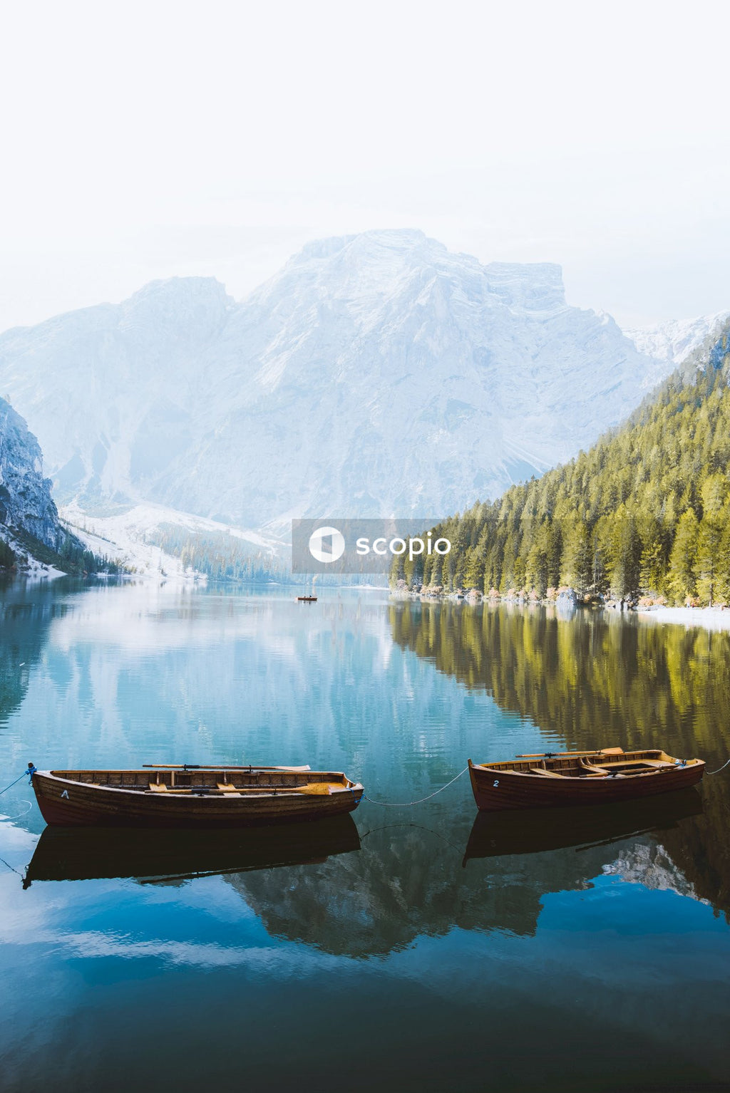 Brown wooden boat on lake near snow covered mountain