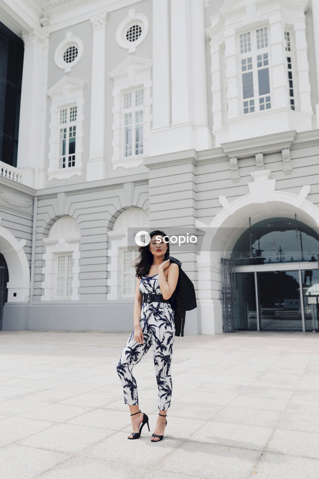 Woman in black and white floral dress standing on white floor tiles