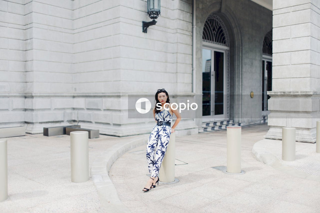 Woman in black and white floral dress standing on gray concrete floor