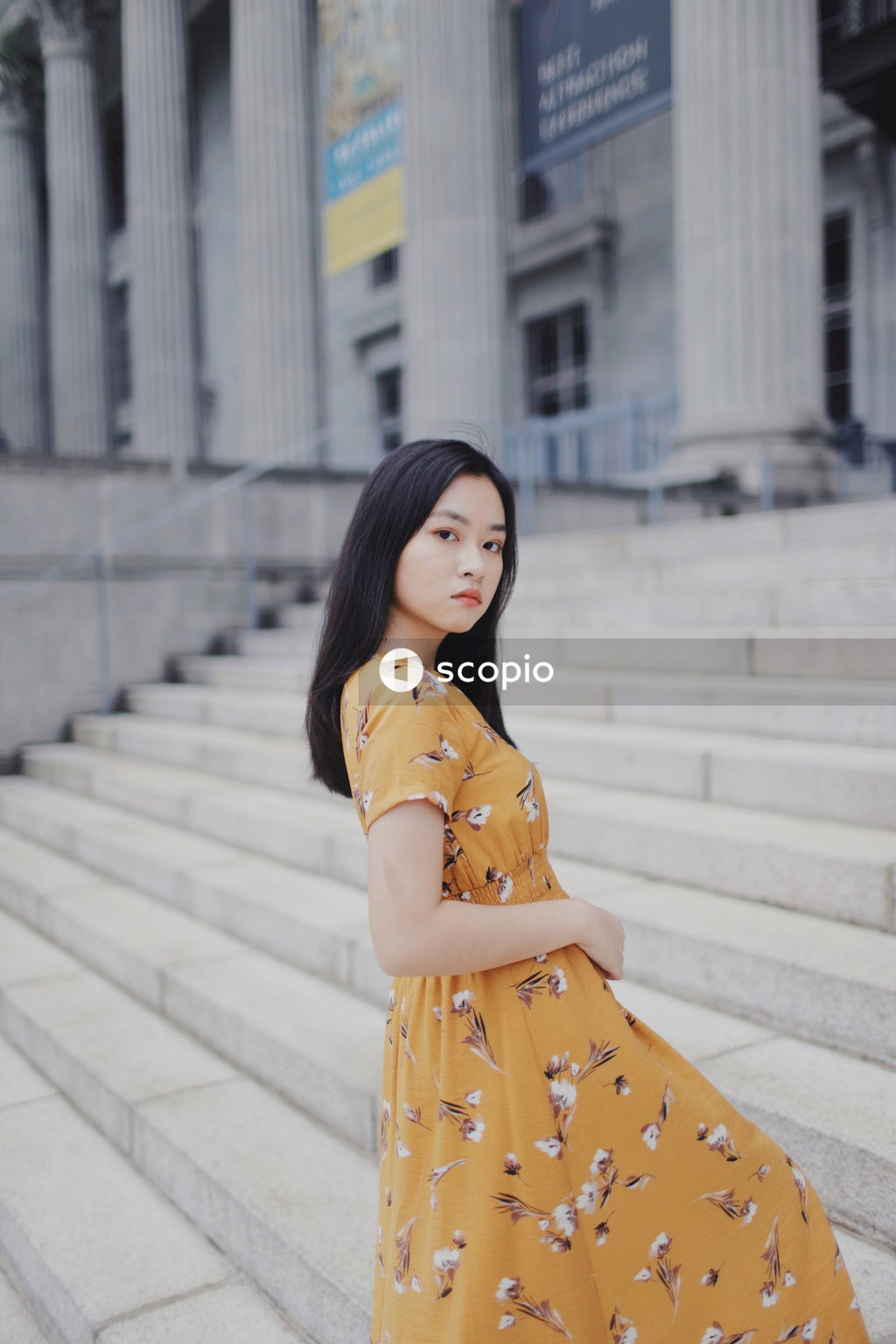 Asian woman in orange dress standing on stairs