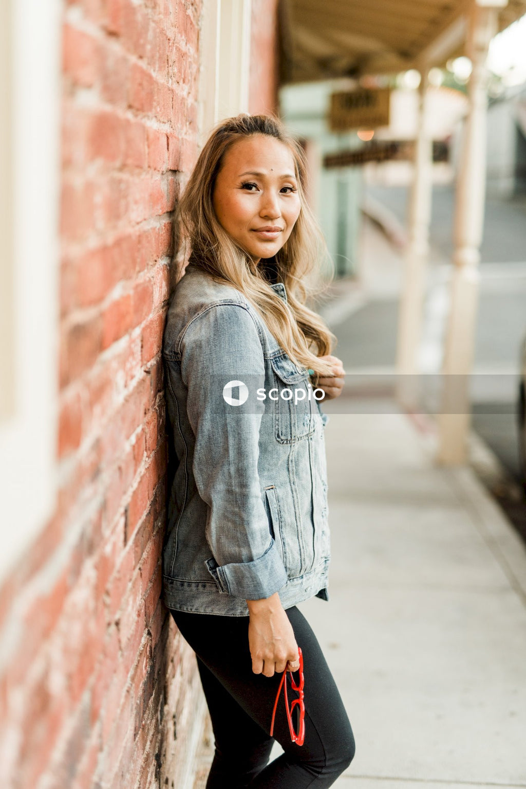 Side view of woman in denim jacket leaning on a wall