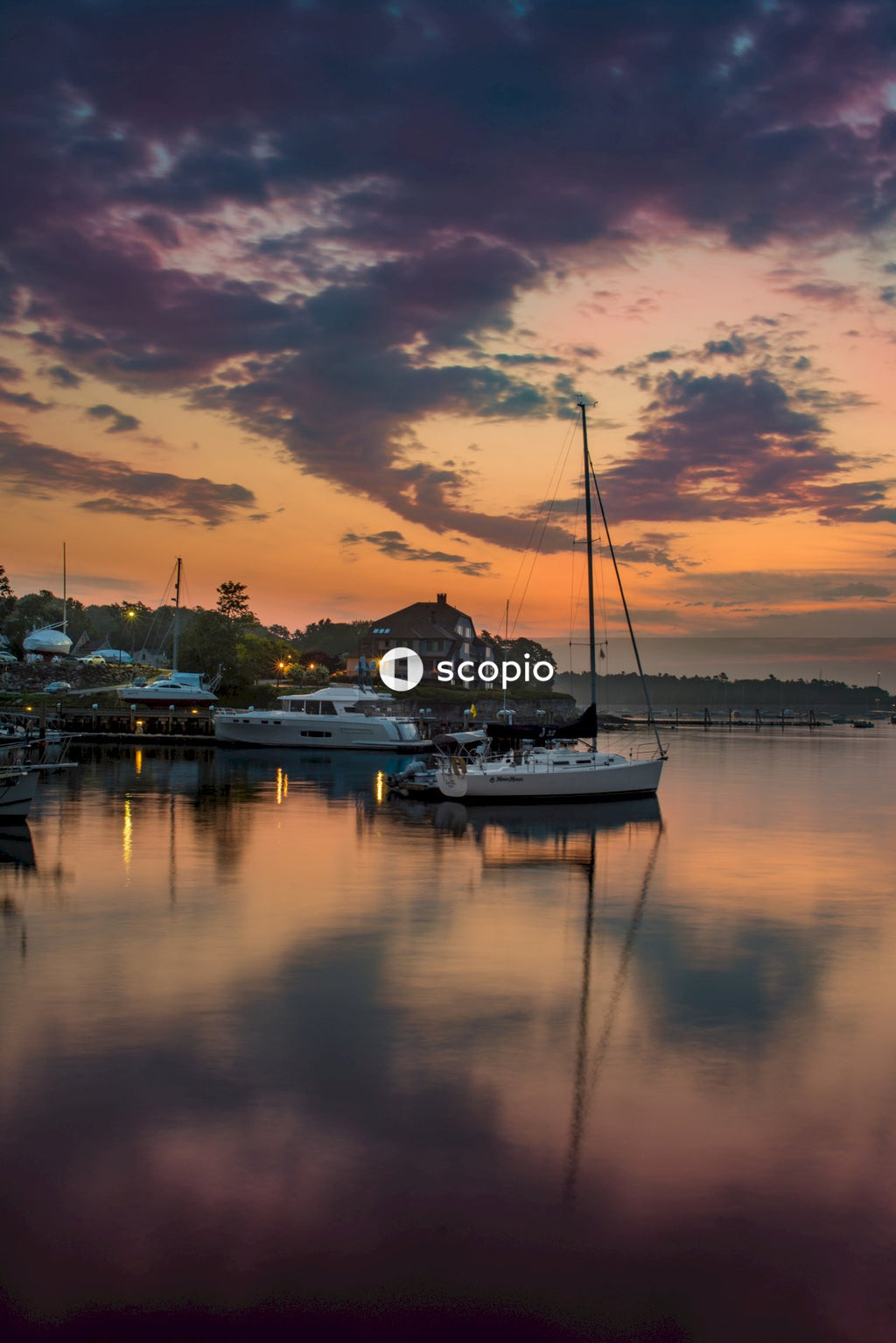 Sailboat Docked in Harbor Silhouetted Against Sunset Sky