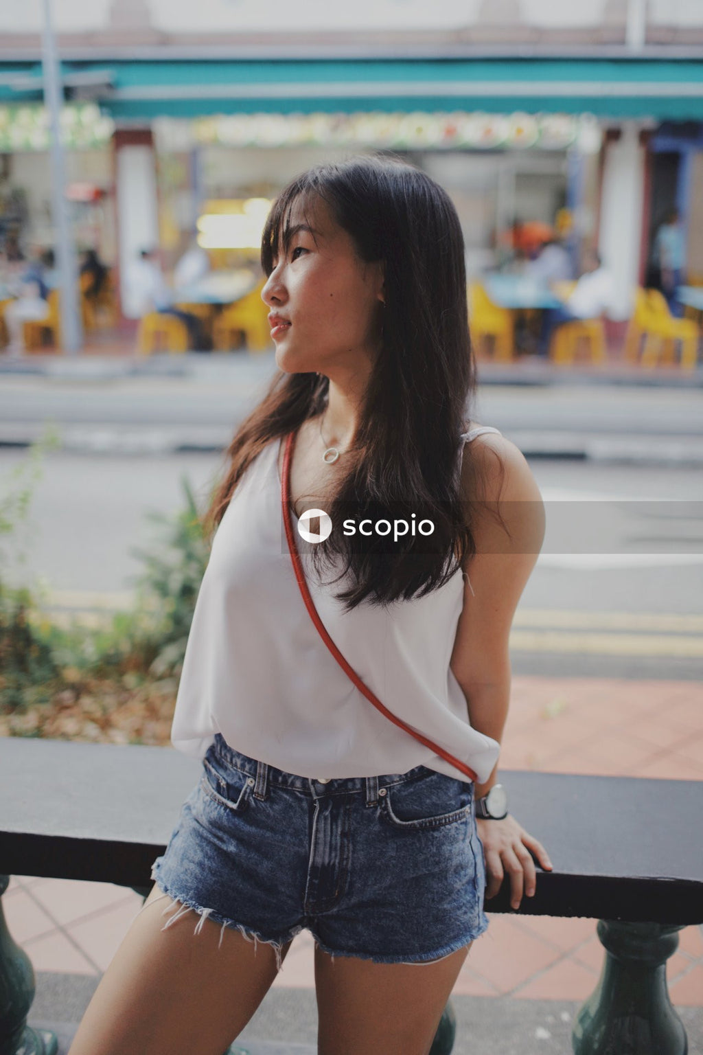 Young woman with bangs wearing light top and short standing on the street