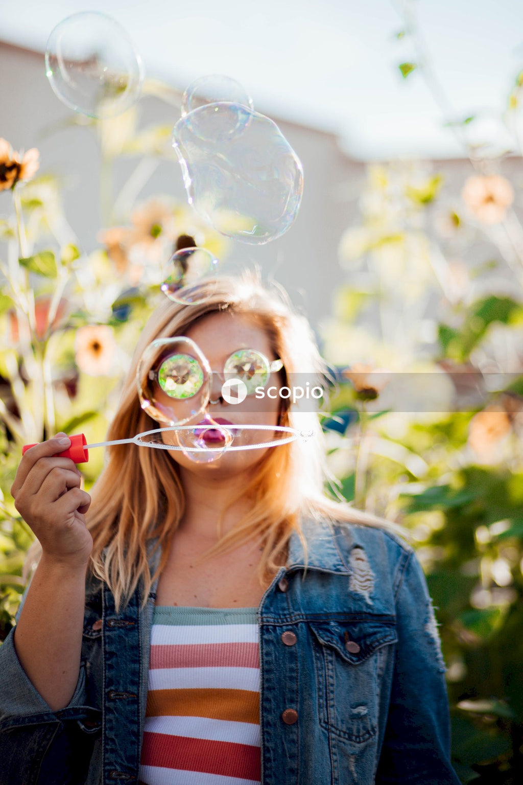 Woman blowing soap bubbles near green plants outdoor during daytime