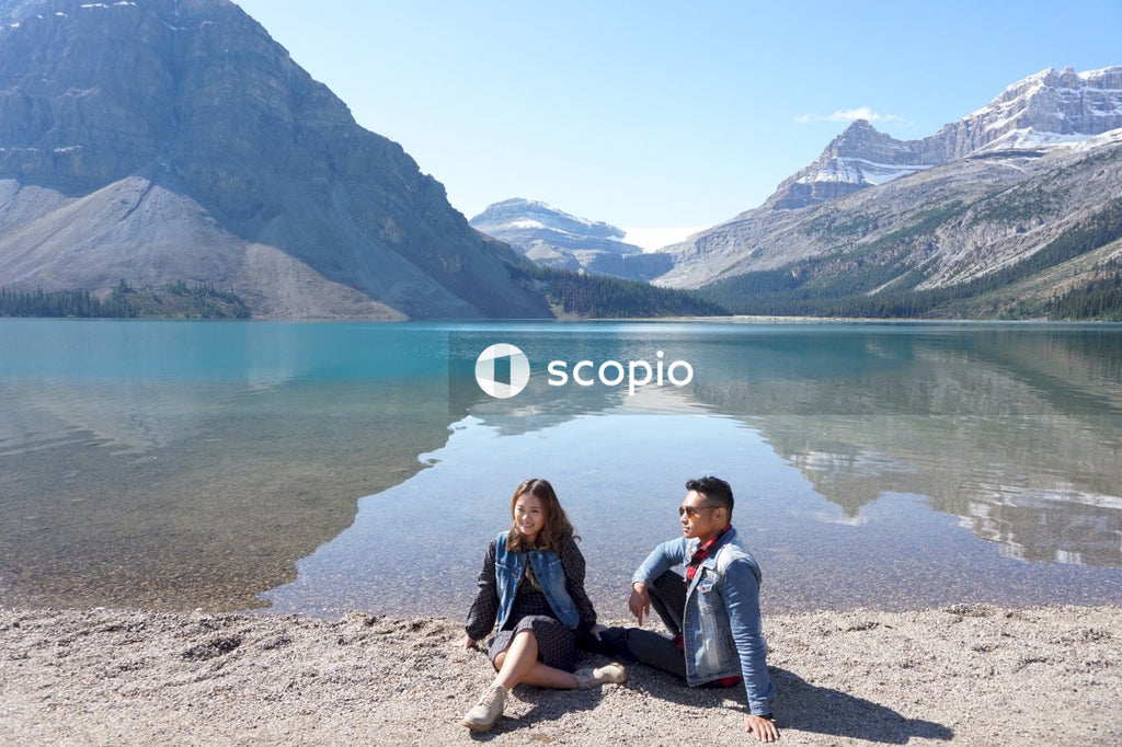 Man and woman sitting on ground by shoreline