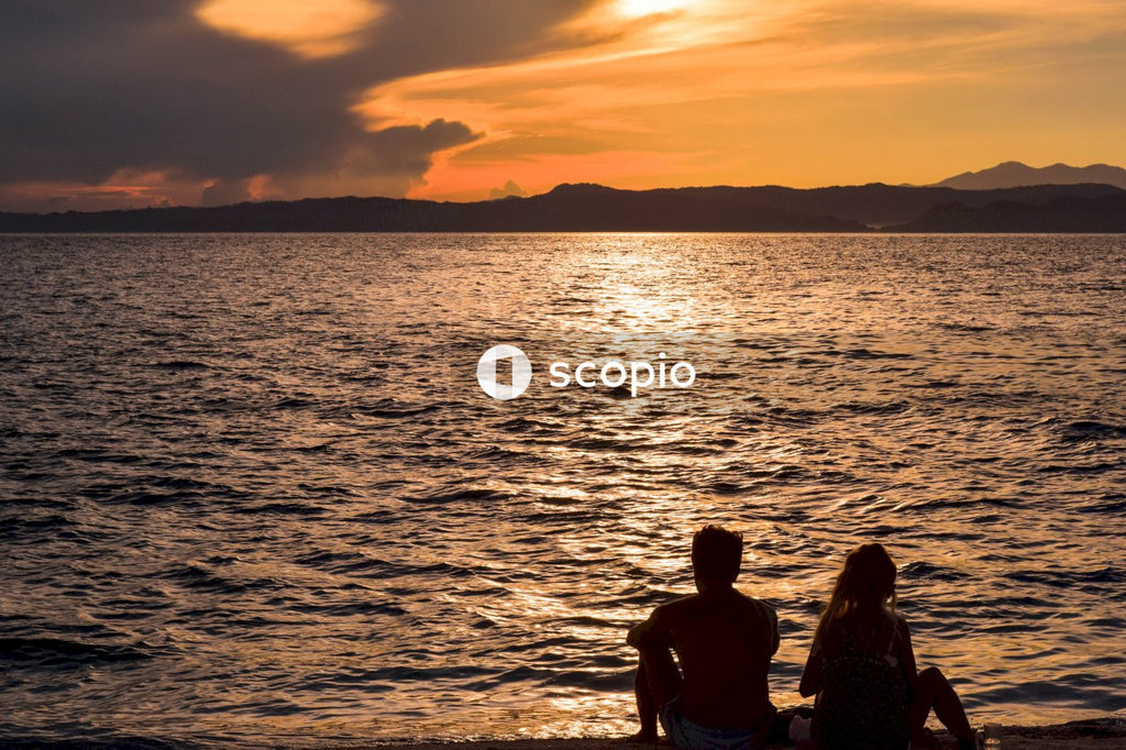 Couple sitting front of sea during golden hour