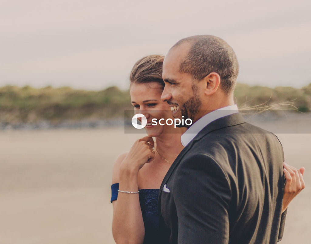 Man in black blazer kissing woman in blue tank top