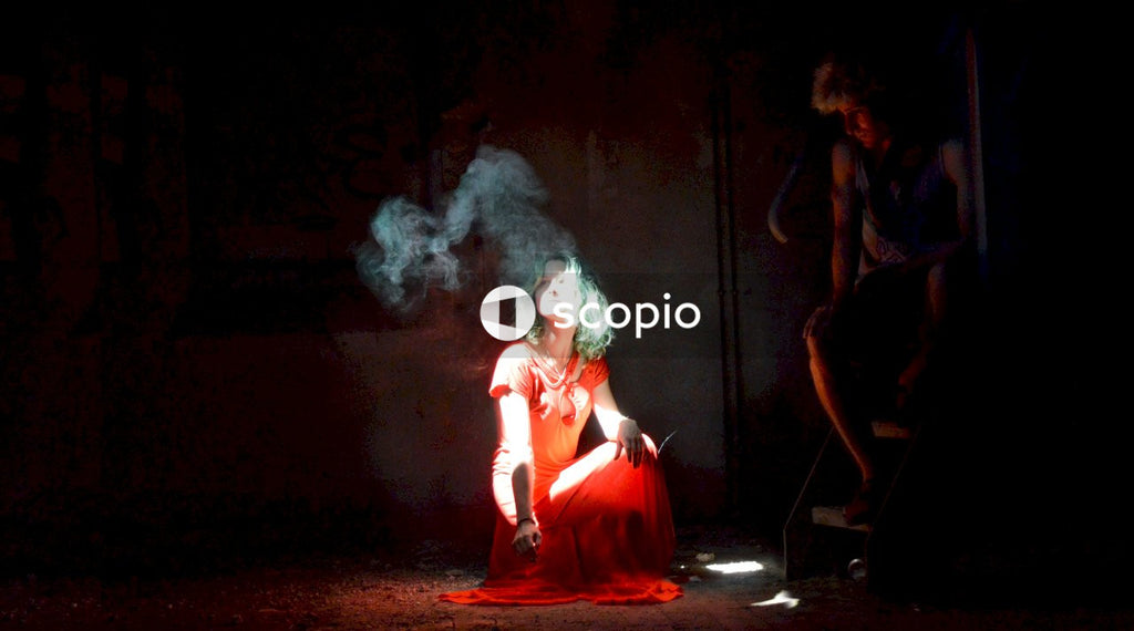 Young woman crouching on stage beside a man sitting on wooden steps