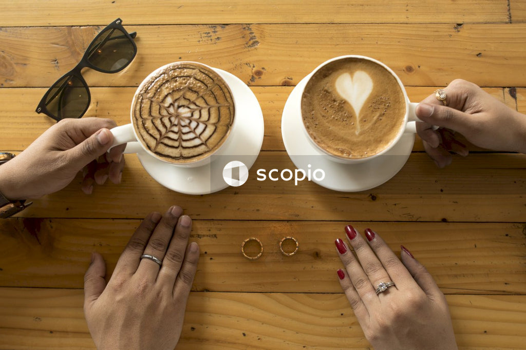 Person holding white ceramic mug with cappuccino