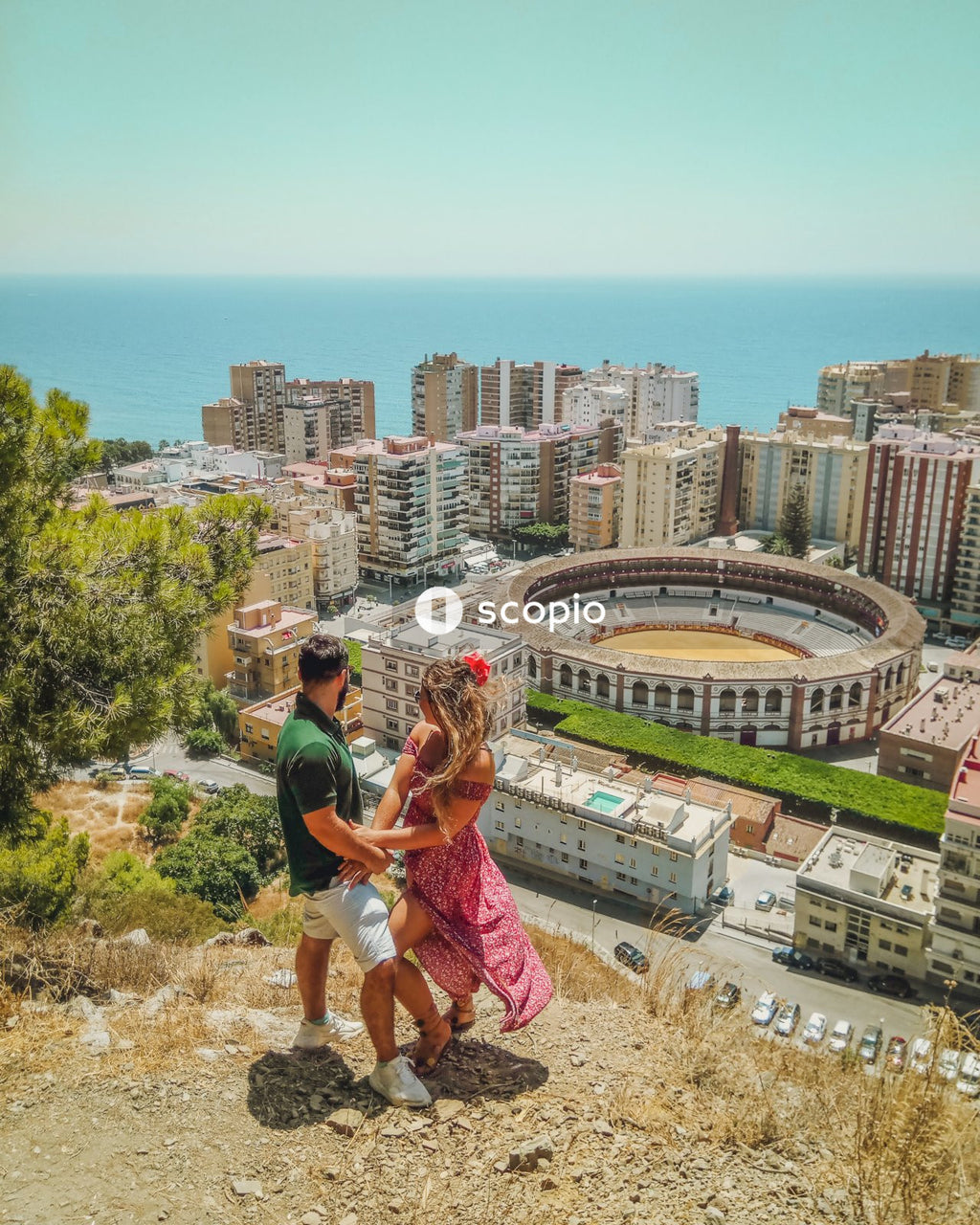 Couple standing over a mountain cliff looking at an amphitheater