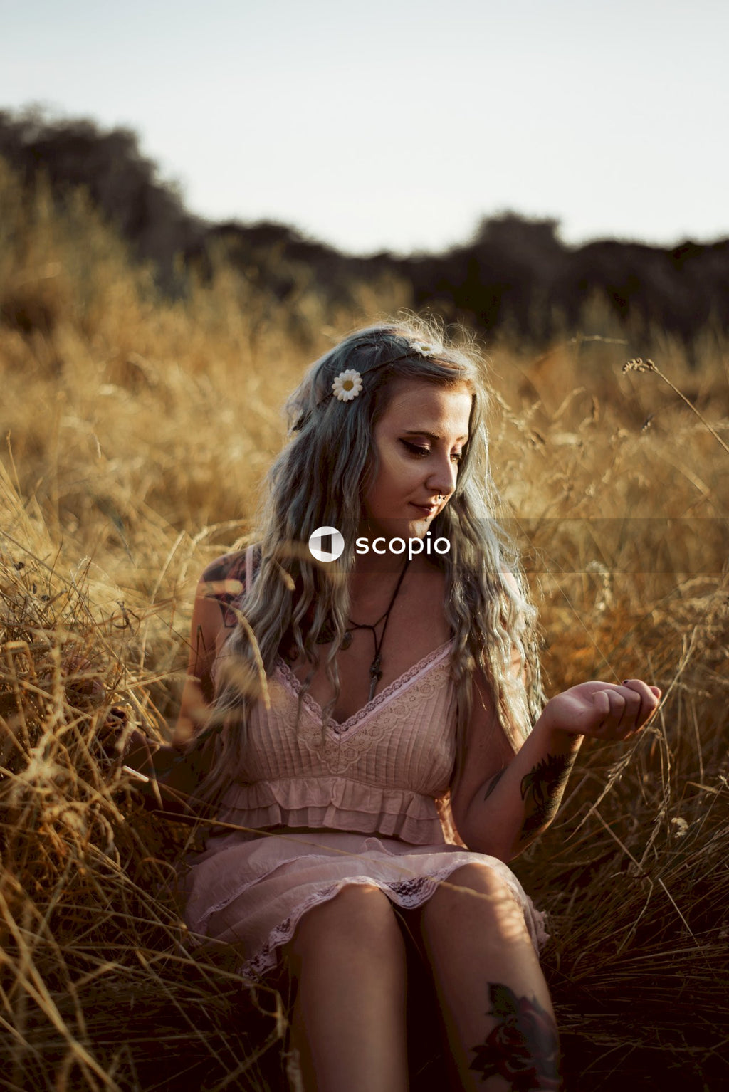 Woman in pink dress sitting on brown grass field