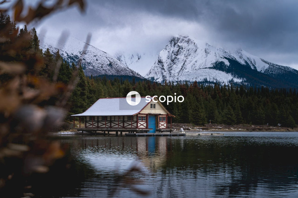 Brown wooden house on lake near green trees and mountain