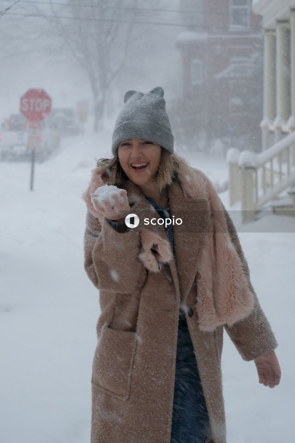 Woman in gray knit cap and brown coat standing beside white metal railings