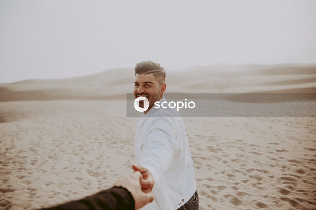 Man holding partners hand walking in desert
