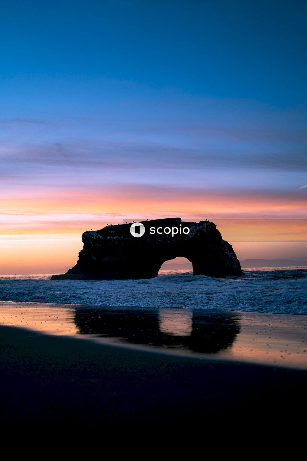 Silhouette of rock in sea during sunset