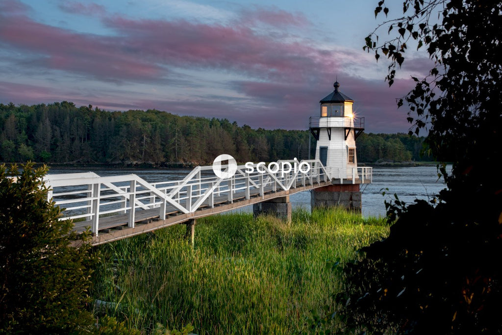 White and black lighthouse near green grass field under cloudy sky