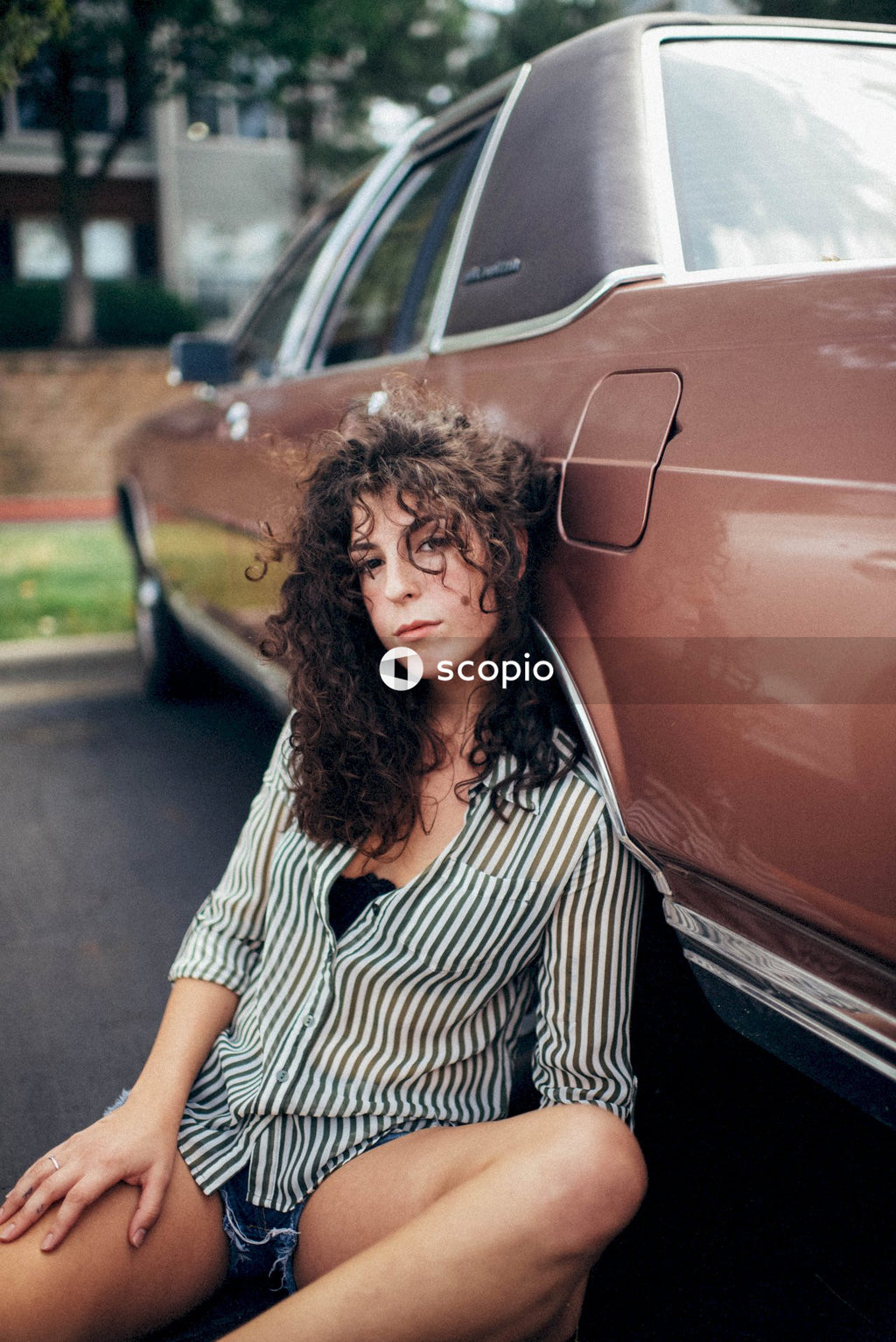 Woman in black and white stripe shirt standing beside red car