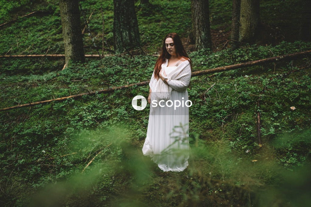 Woman in light dress standing on forest
