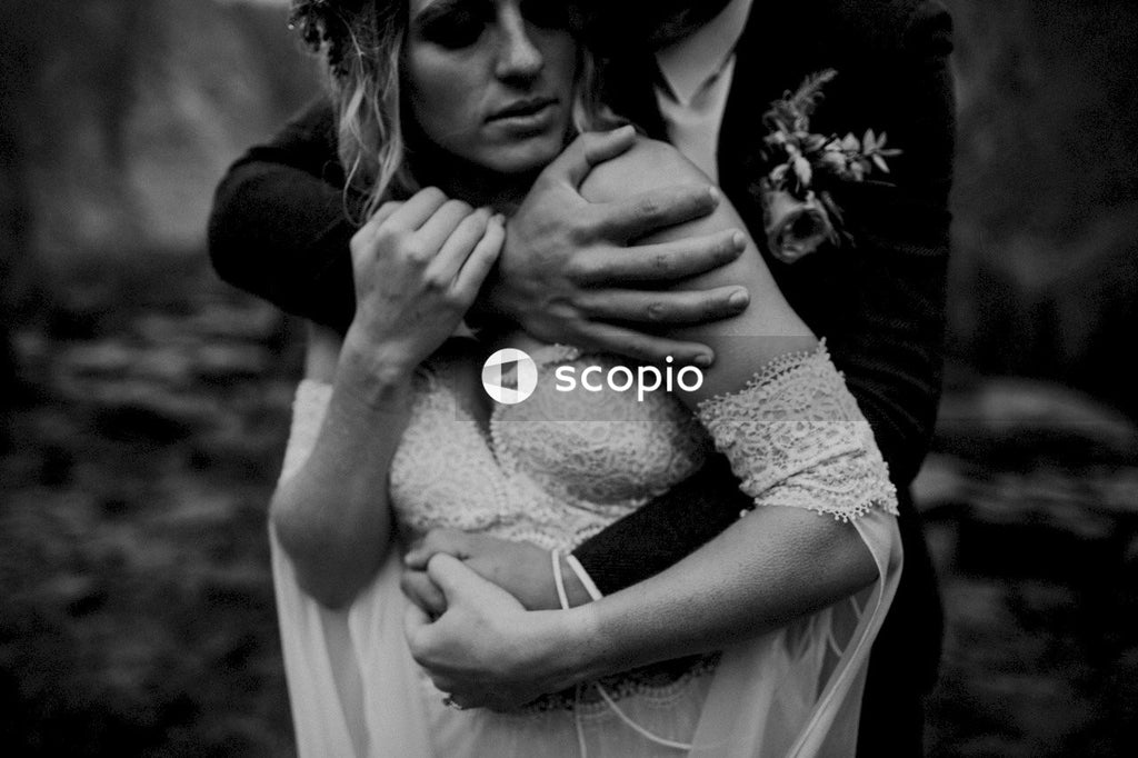 Woman in white lace dress hugging man in black suit