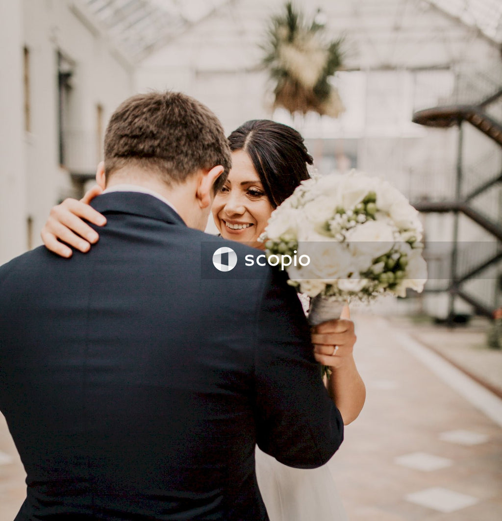 Man in black suit holding white flower bouquet