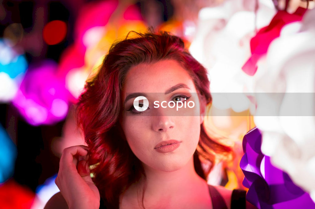 Woman standing in front of out of focus colorful lights