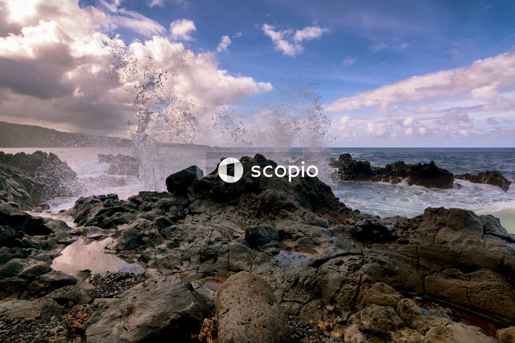 Brown rocky shore under blue sky and white clouds