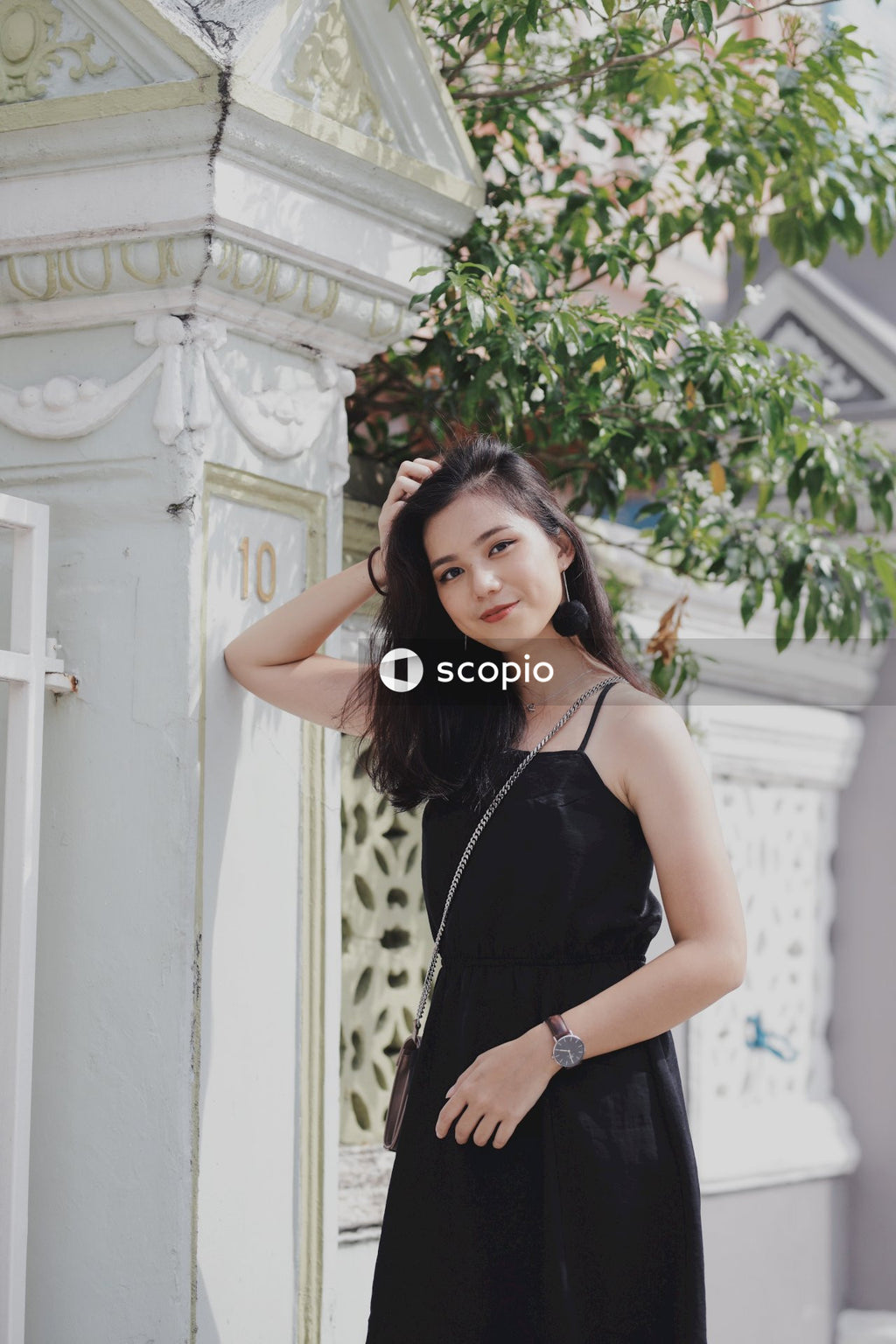 Asian girl in dark dress standing next to fence