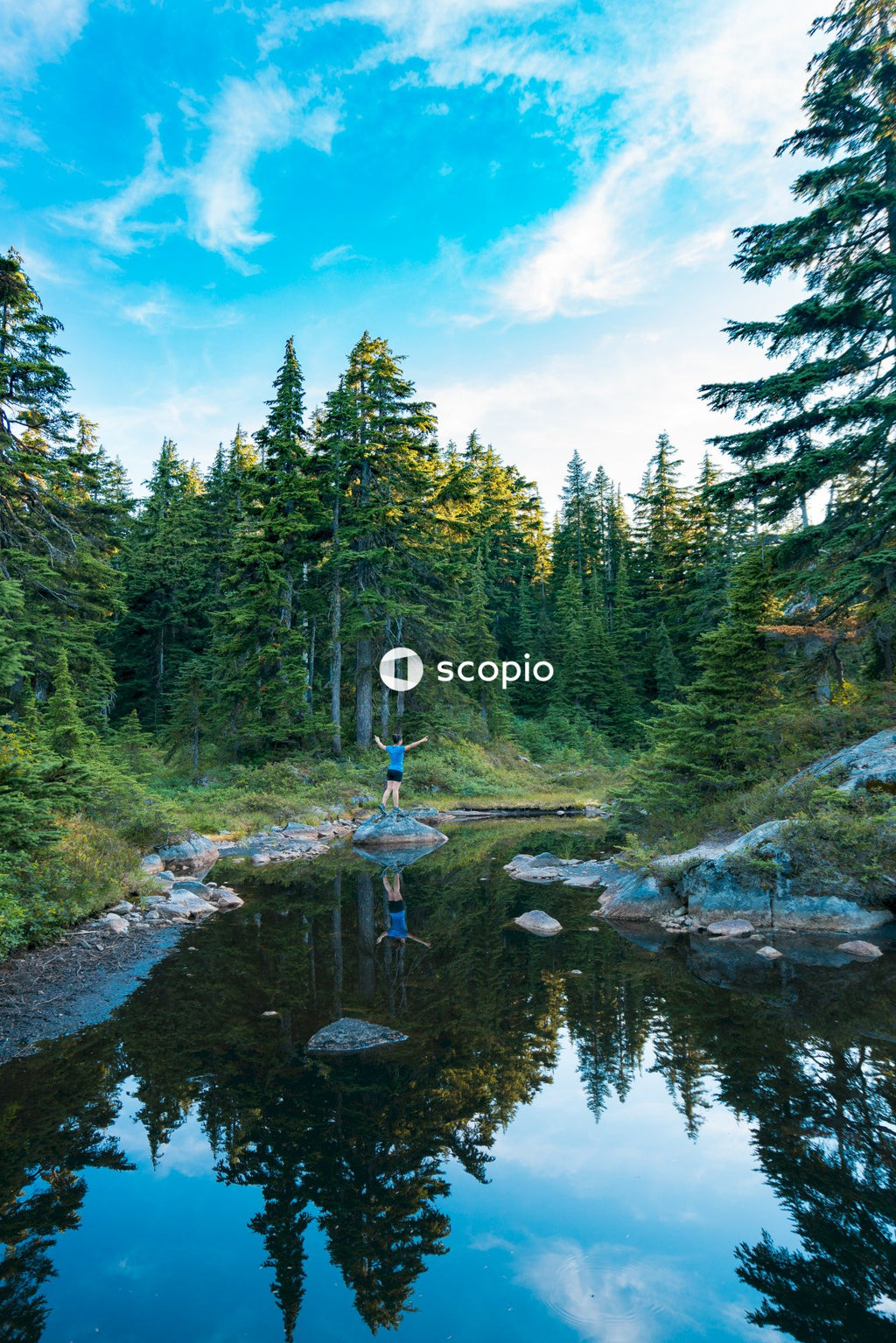 Person opening their arms and standing on rock in a river