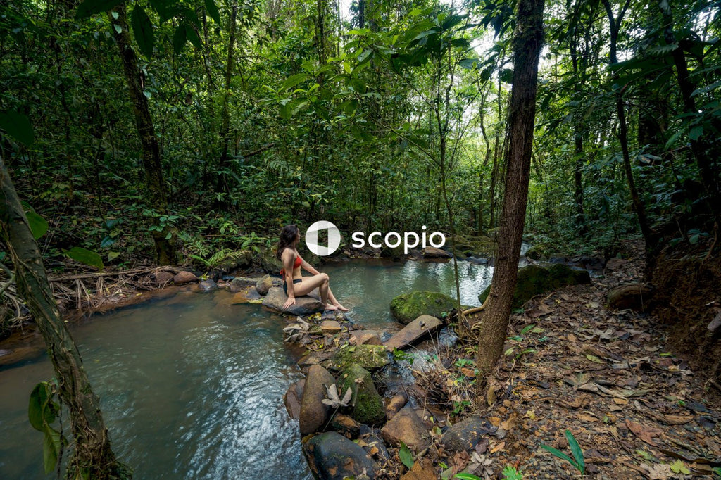 Woman in  bikini sitting on rock in river
