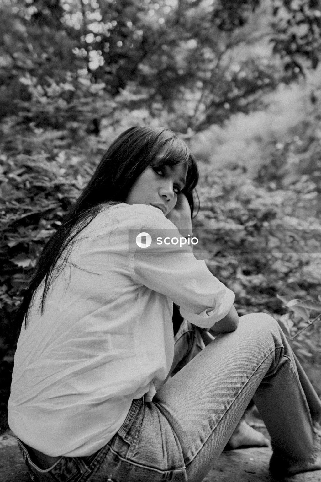 Woman in white long sleeve shirt and gray pants sitting on rock
