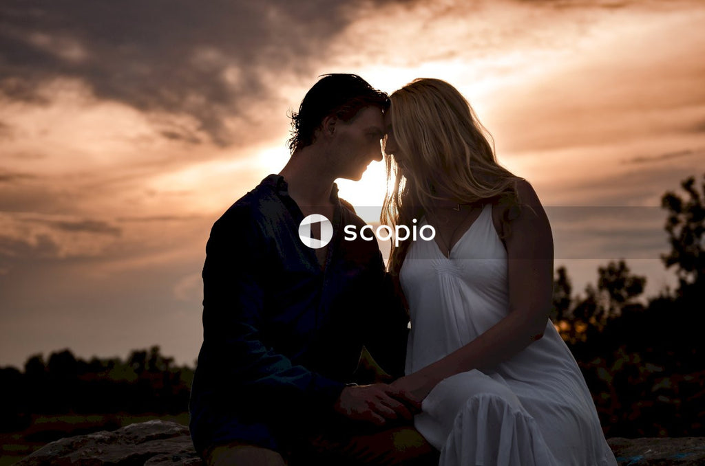 Man and woman sitting beside each other outdoor at sunset