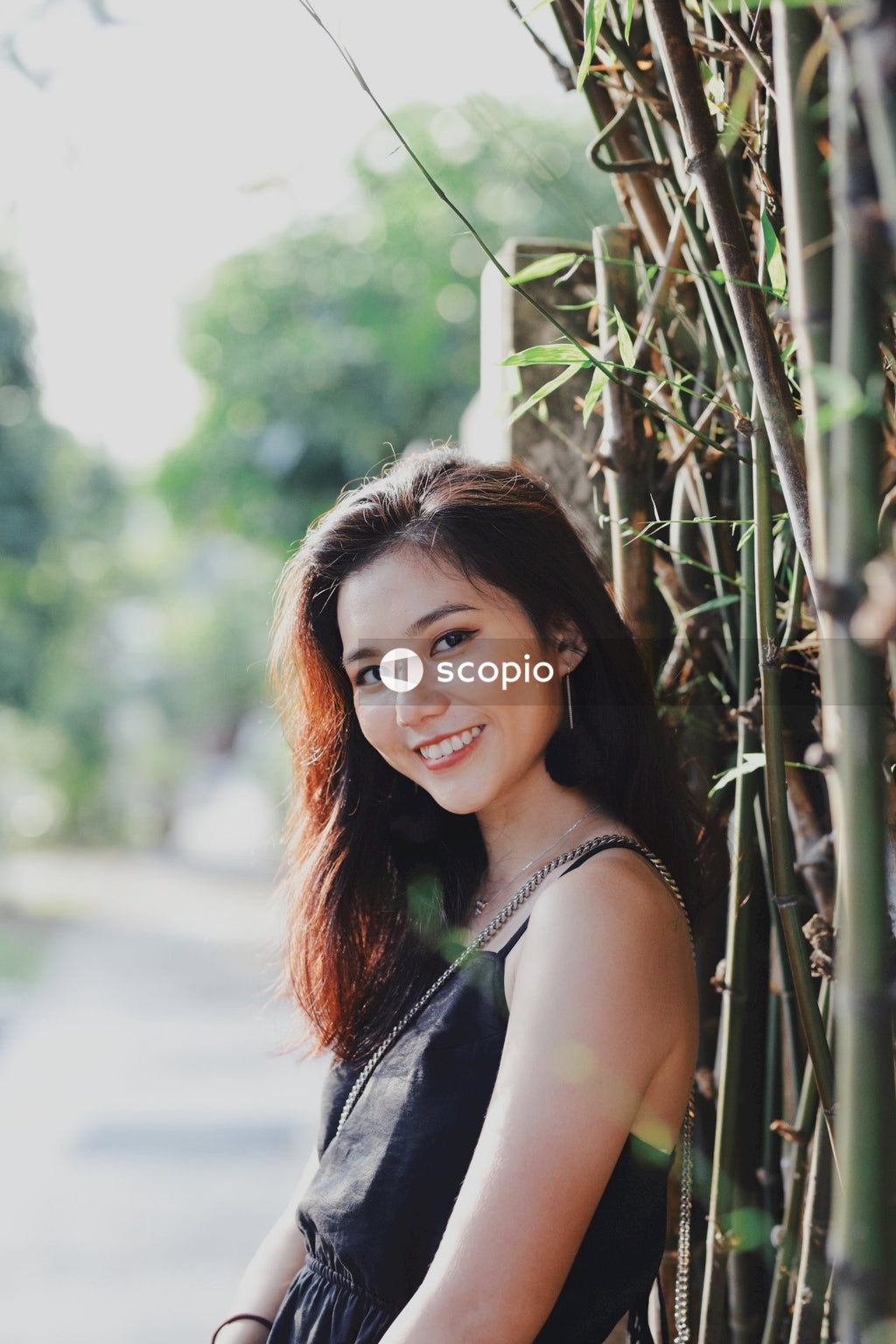 Woman in dark dress posing near flowers bushes